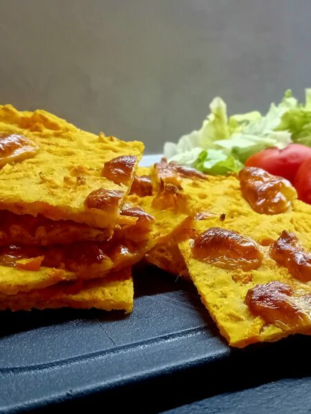 Schiacciata di carote dorata e croccante con sopra pezzetti di scamorza, accompagnata da pomodorini datterini e insalata